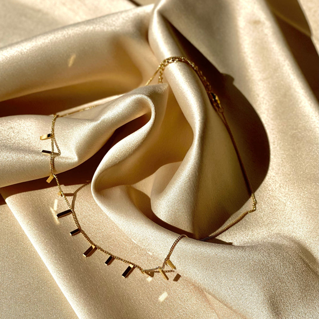 Gold necklace on beige satin fabric
