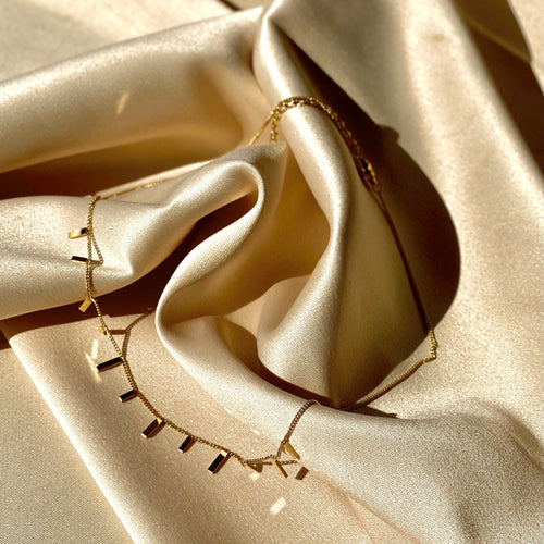 Gold necklace on beige satin fabric