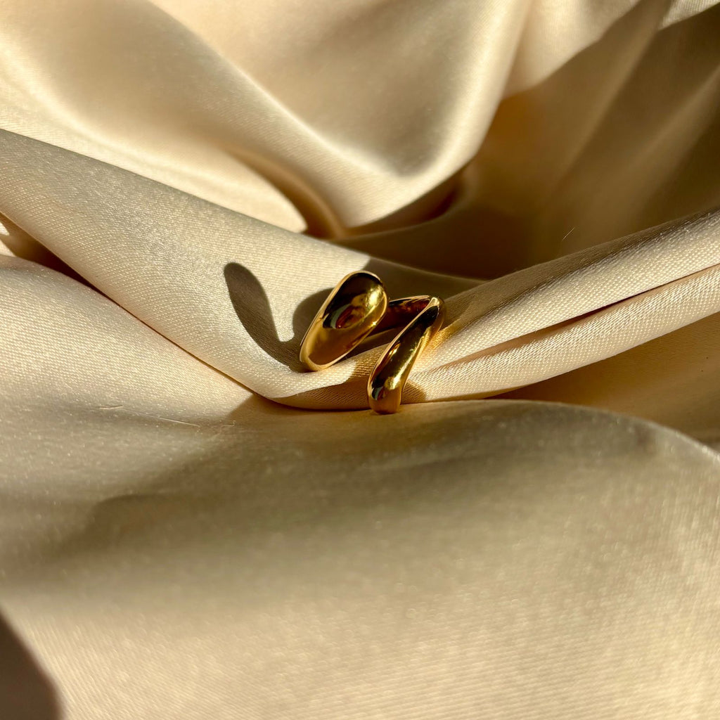 Gold snake-shaped jewelry on beige satin fabric