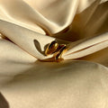 Gold snake-shaped jewelry on beige satin fabric
