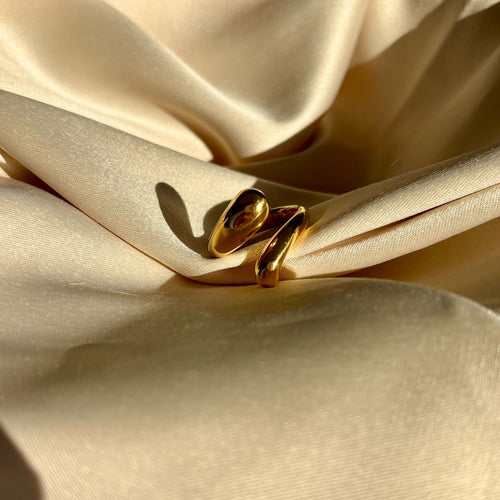 Gold snake-shaped jewelry on beige satin fabric