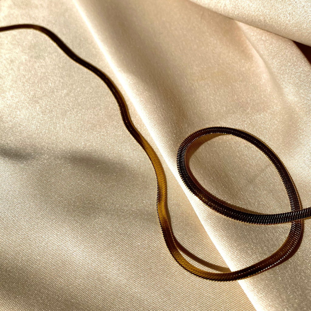 Close-up of beige fabric with a gold necklace on top