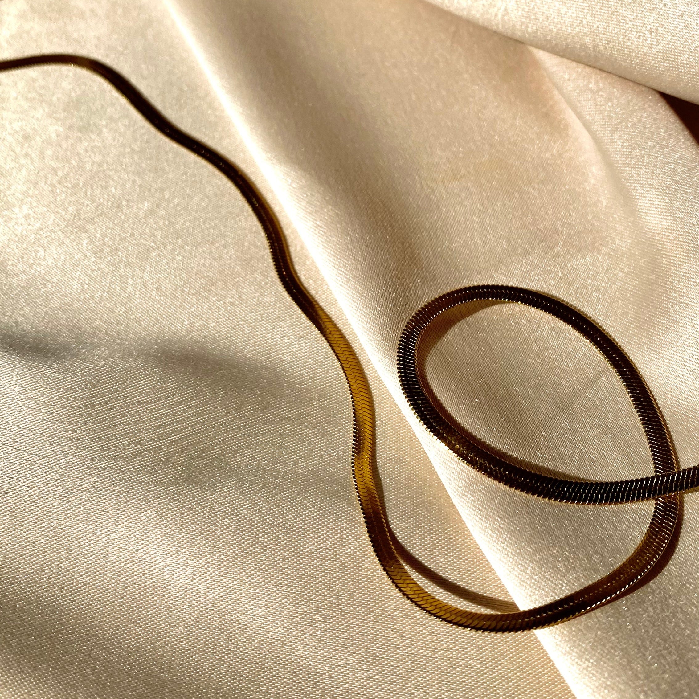 Close-up of beige fabric with a gold necklace on top